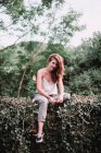 Porträt junge Frau sitzt auf Gartenzaun und blickt in Kamera — Stockfoto