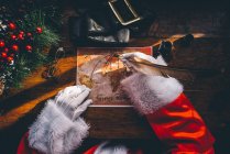 Ernte der Weihnachtsmannhände mit Federschmuck auf der Weltkarte — Stockfoto