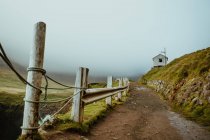 Pathway with rural fence running to countryside cottage in misty highlands — Stock Photo