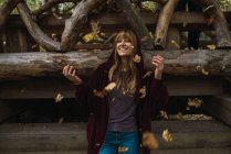 Sorridente ragazza bruna che gioca con le foglie nel parco — Foto stock
