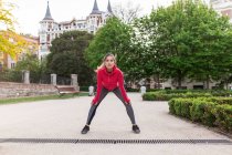Portrait de fille en tenue de sport s'étirant au parc de la ville — Photo de stock