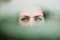 Портрет жінки з зеленими очима, що дивиться в розмиту тріщину . — стокове фото