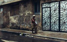 CUBA - 27 de agosto de 2016: Vieja caminando por el pavimento de la calle en el barrio pobre . - foto de stock
