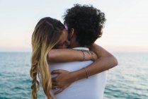 Jeune couple heureux embrassant sur jetée sur océan sur toile de fond — Photo de stock