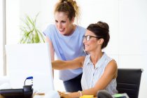 Portrait of businesswoman showing something on computer monitor to colleague in office. — Stock Photo