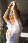 Portrait de fille brune posant avec les bras levés près de la fenêtre dans une pièce abandonnée avec des graffitis — Photo de stock