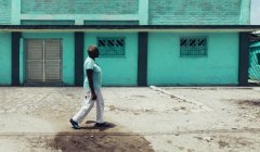 Kuba - 27. August 2016: Seitenansicht einer Frau, die am blauen Gebäude entlang geht — Stockfoto