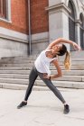 Sportliche Frau streckt sich am Straßenrand aus — Stockfoto