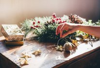 Cultivo de manos femeninas confeccionando decoraciones navideñas en la mesa - foto de stock