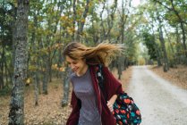 Fröhliches Mädchen mit Rucksack im Wald unterwegs — Stockfoto