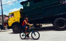 CUBA - 27 DE AGOSTO DE 2016: Vista lateral de un niño montando en bicicleta por la calle - foto de stock