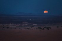 Vista panorámica a las arenas desérticas vacías y el sol tenue en el crepúsculo . - foto de stock