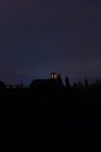 Силуэт колокольни с освещенными окнами ночью — стоковое фото