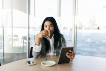 Retrato de mulher de negócios com tablet na mão bebendo chá e olhando para a câmera — Fotografia de Stock