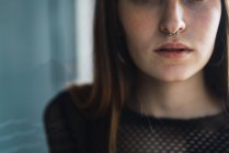 Crop young brunette with nose piercing looking at camera — Stock Photo