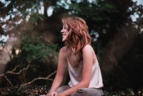 Seitenansicht einer lächelnden Frau, die im Garten posiert — Stockfoto