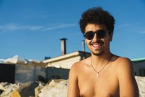 Retrato de homem em óculos de sol posando na praia de seixos — Fotografia de Stock