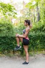 Girl stretching leg before jogging at park alley — Stock Photo