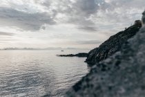 Морской пейзаж прибрежных скал и рыбацкая лодка в море — стоковое фото