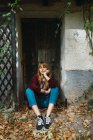 Портрет дівчини брюнетки в светрі сидить на землі біля дверей в парку і дивиться в сторону — стокове фото