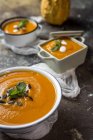 Close up view of row of cream of pumpkin in bowls on stone surface — Stock Photo
