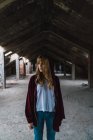 Girl in red hoodie jacket posing in derelict building and looking away — Stock Photo