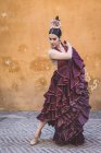 Flamenco dancer wearing typical long skirt costume posing over street wall on background — Stock Photo