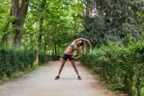 Girl stretching aside on park alley before workout — Stock Photo