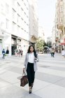 Femme d'affaires élégante et souriante avec sac à main marchant sur la scène de la rue — Photo de stock