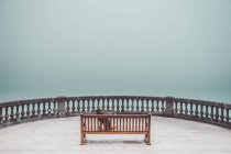 Chien assis sur banc sur terrasse au-dessus de la mer brumeuse — Photo de stock