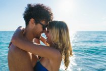 Vista lateral do casal amoroso abraçando na praia — Fotografia de Stock