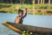 BENIN, ÁFRICA - 31 DE AGOSTO DE 2017: Jovem africana topless sorrindo para a câmera enquanto remo em barco tradicional de madeira — Fotografia de Stock
