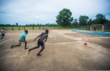 Бенин, Африка - 31 августа 2017 года: Группа мальчиков играет в футбол на бетонном поле  . — стоковое фото