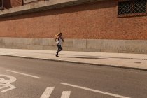 Спортивна жінка, що біжить на сонячно освітленій стороні — стокове фото