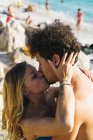 Portrait of loving couple kissing on pebble beach — Stock Photo