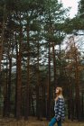 Vue latérale de la fille en chemise à carreaux marchant dans la forêt — Photo de stock