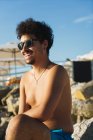 Усміхнений чоловік в сонцезахисних окулярах позує на тропічному пляжі — стокове фото