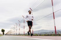 Low angle view of man in sportswear jogging on race track and looking forward . — Stock Photo