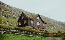 Low angle view of wooden house on rocky highlands slope — Stock Photo