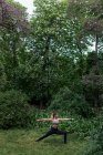 Sporty woman performing yoga asana among woods in park — Stock Photo