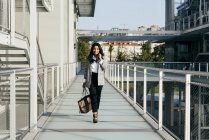 Elegante Geschäftsfrau geht auf Balkondurchgang und blickt in die Kamera — Stockfoto