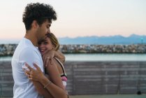 Side view of man embracing girlfriend on pier — Stock Photo