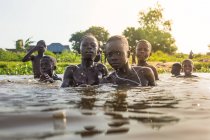 BENIN, AFRIQUE - 31 AOÛT 2017 : Groupe d'enfants nageant dans la rivière et regardant la caméra sur fond tropical . — Photo de stock
