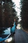 Вид збоку жінки, що виходить з вікна автомобіля на лісовій дорозі — стокове фото