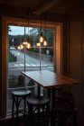 Mesa de madeira e bancos de bar perto da janela — Fotografia de Stock