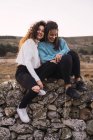 Две обнимающие женщины сидят на скалистом склоне — стоковое фото