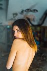 Topless woman looking over shoulder at camera in abandoned building — Stock Photo