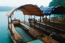 Fila di barche turistiche ormeggiate sulla riva del lago di montagna — Foto stock