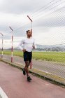 Man in sport outfit running along fence — Stock Photo