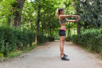 Vue latérale d'une fille sportive effectuant du yoga asana dans une allée du parc — Photo de stock